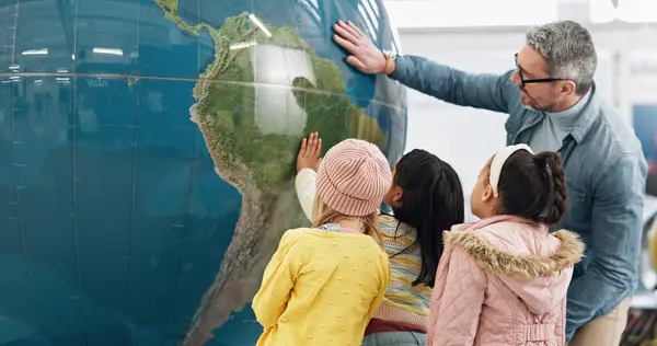 Science, world and students learning about the earth with a teacher at school for growth or development. Geography, globe or planet with a man teaching kids about climate change or global warming.