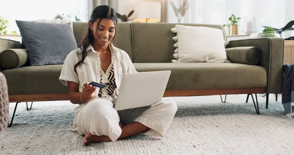 Woman, laptop and credit card for home online shopping, fintech payment and e commerce on living room floor. Young person typing on computer for internet banking, web subscription or loan on carpet.