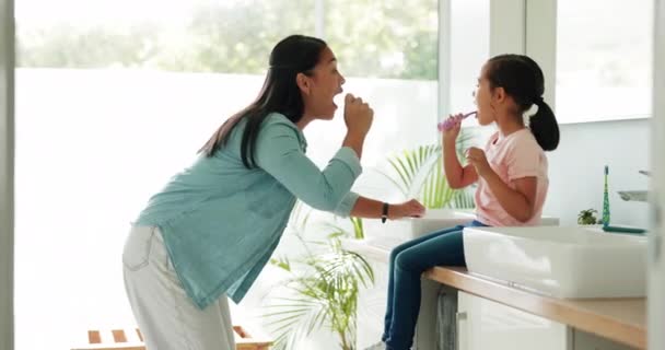 妈妈教她的孩子在他们现代家庭的浴室里一起刷牙 健康和年轻的妈妈在家里帮她的女儿做早上的日常口腔护理 — 图库视频影像