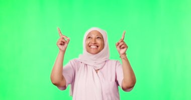 Stüdyoda reklam ya da promosyon için yeşil ekranı olan pazarlama, işaret etme ve müslüman bir kadın. Mutlu, gülümseyen ve olgun İslamcı bir kadın modeli. Renkli anahtar arkaplanlı bir el hareketi..