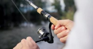 Hands, reel fishing rod and lake for catch, sport or hobby in nature, forest or holiday with tools for food. Person, fisherman and closeup for fish, river or woods for sustainability in environment.