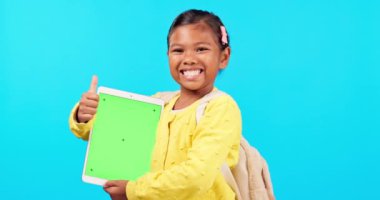 Mutlu kız, yeşil ekranda aferin ve tablet sosyal medya için mavi stüdyo geçmişine karşı. Emojisi olan küçük bir çocuğun portresi, evet işareti ya da teknoloji uygulaması ya da başarı için onay.