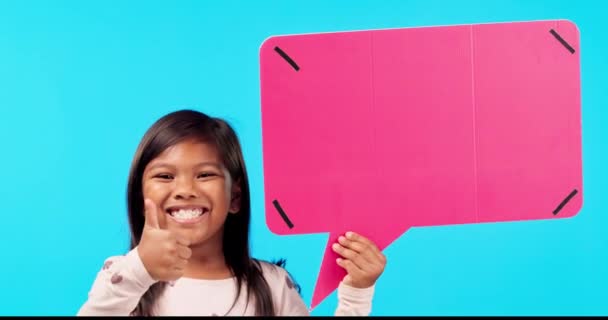 快乐的小女孩 竖起大拇指 指着说话泡泡在一个蓝色工作室背景的模仿聊天 女孩或小孩的画像 带着类似情调的微笑 是的标志或社交媒体的成功 — 图库视频影像