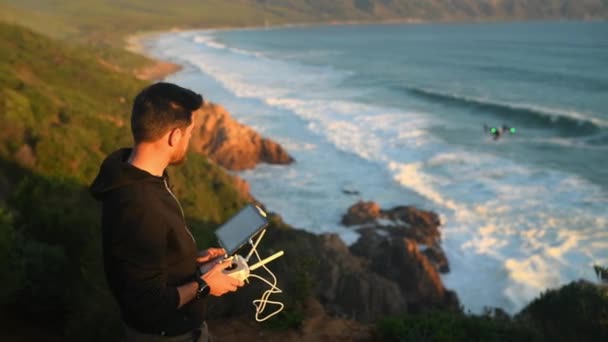 テクノロジー そして夏の間にビデオ映像のために自然界でドローンを飛行する男 海沿いのロボットを海岸で操縦するリモコンを使用した人とのビーチ ビュー — ストック動画