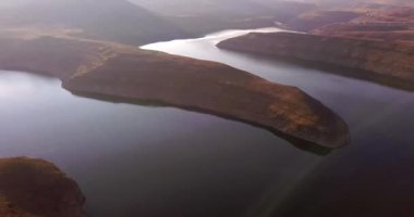 Sabah, dağdaki göl manzarası ve drone nehirde, suda veya doğada güneşle birlikte. Güneş doğarken vadide ya da gökyüzü ve karayla birlikte açık havada sisli baraj manzarası.