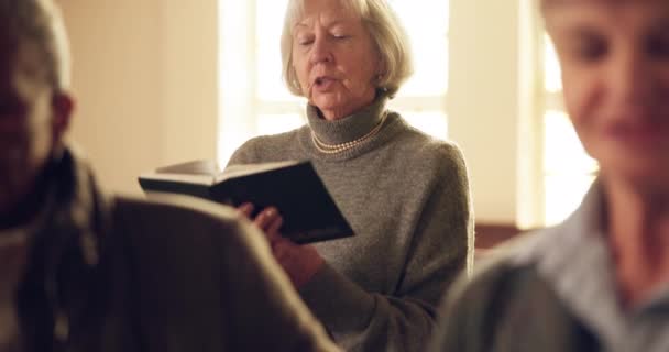 シニアの女性 そして信仰 読書で礼拝 賛美の本で歌います 高齢のクリスチャン女性 サーモンでフォーカスと聖歌 敬意や精神的なマインドフルネスとの調和 — ストック動画