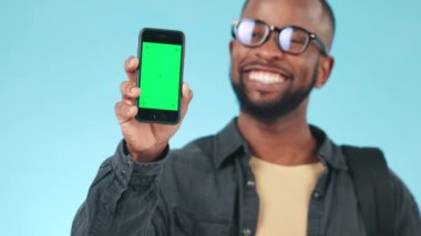 Stüdyoda reklam ve pazarlama için bir model olan siyah adamın yeşil ekranı, telefonu ve yüzü. İşaretleyiciler, krom anahtar ve mavi arka planda cep telefonu olan Afrikalı erkek modelin portresi