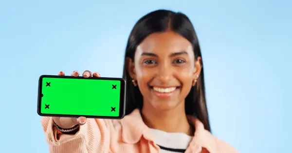 Smartphone green screen, studio portrait and happy woman show internet connection, mobile promotion or app chroma key. Tracking markers, cellphone mockup space and tech person face on blue background.