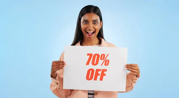 Woman, promotion poster and portrait with sale, discount and billboard in studio. Excited, smile and happy from savings and deal paper with banner and promo with blue background and price decrease.