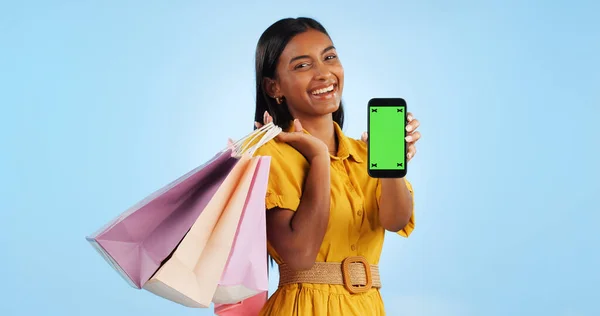 Smartphone green screen, shopping bag and portrait of happy woman show online shop, retail market or studio omnichannel. Tracking markers, phone chroma key or mockup space customer on blue background.