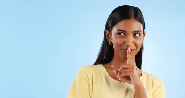 Secret, gossip and woman with finger on lips, smile and announcement on a blue background. Person, girl and model with privacy, mockup space and drama news with surprise, emoji and whisper with shush.