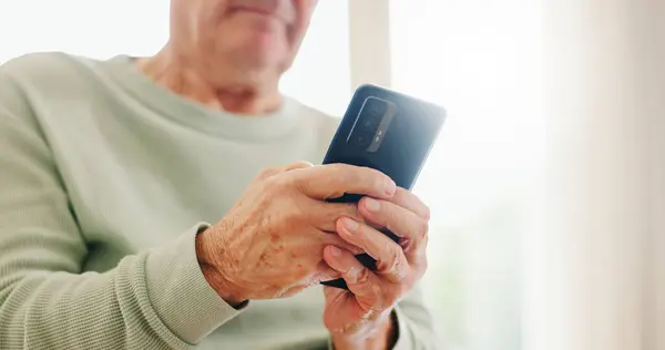 Home, closeup and senior hands with a cellphone, typing and connection with social media, digital app and contact. Old man, pensioner or mature guy with a smartphone, mobile user and search internet.