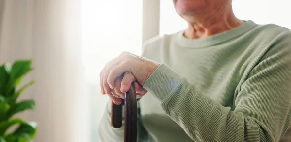 Hands, old person with disability and walking stick, closeup with wellness and retirement. Senior care, cane to help with balance and support, Parkinson disease or arthritis, sick and health issue.