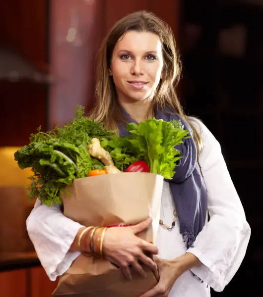 Woman, portrait and vegetable bag in kitchen for nutrition meal, healthy green salad or vegan choice. Female person, face and groceries for eating organic dinner diet, vitamin food or clean spinach.