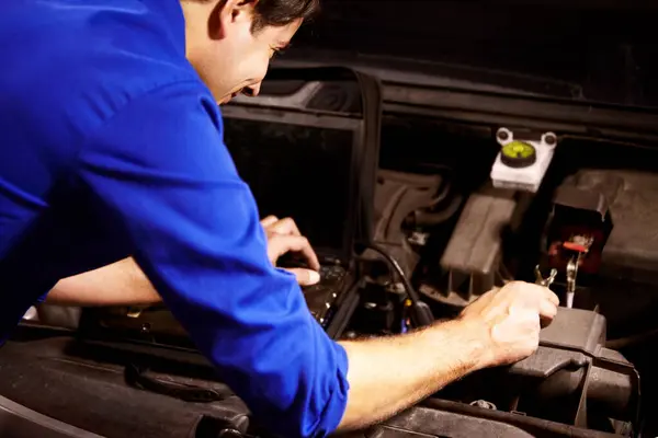 Hands, car or repair and a mechanic man in a workshop as an engineer looking at the engine of a vehicle. Garage, service or maintenance with a young technician working under the hood of an automobile.