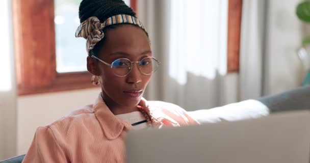 非洲妇女 笔记本电脑和沙发 在家做远程工作 带着眼镜 阅读或分析密码交易 有思想 想法或股票市场研究的企业家 投资人和交易者 — 图库视频影像