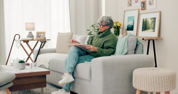 知識のためのリビングルームでリラックスするためのシニア女性 本と読書 高齢の女性 引退のためのラウンジに焦点を当てる 家庭でのソファーでの文学と趣味 — ストック動画