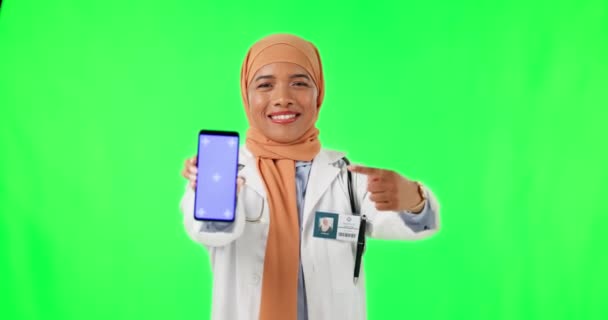 イスラム教徒の女性 スタジオの背景に広告のための緑の画面上で電話を指しています トラッキングマーカーとスマートフォンへの女性医療や医療の専門家ポイントの肖像 — ストック動画