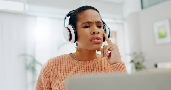 Remote work, black woman and thinking on a laptop for business, online planning or a strategy. House, music and serious African freelance worker with a podcast, headphones and streaming sound on a pc.