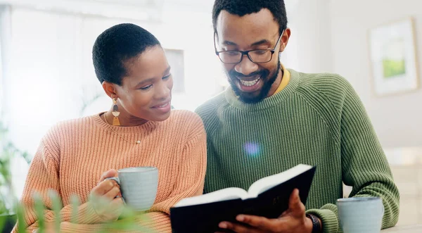 Home, relax and black couple with smile, reading a book or relax with religion, love or bonding together. Romance, apartment or man with woman, scripture or bible with Christian, hope or conversation.