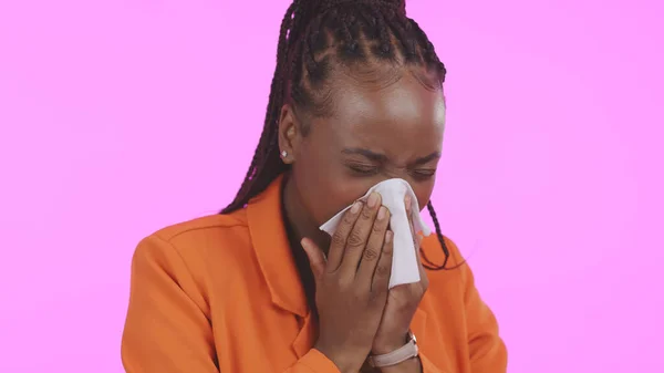 Black woman, blowing nose and sick with allergies, sneezing and sinus infection with health on pink background. Hay fever, wellness and toilet paper, medical condition with illness or virus in studio.