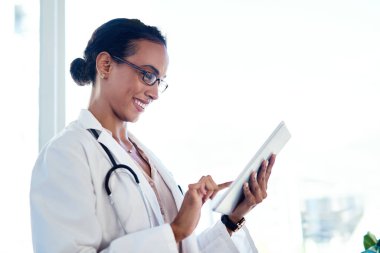 Sağlık hizmetleri bilgileriyle dolu bir dünyaya bağlandı. Genç bir doktor danışma odasında dijital tablet kullanıyor.