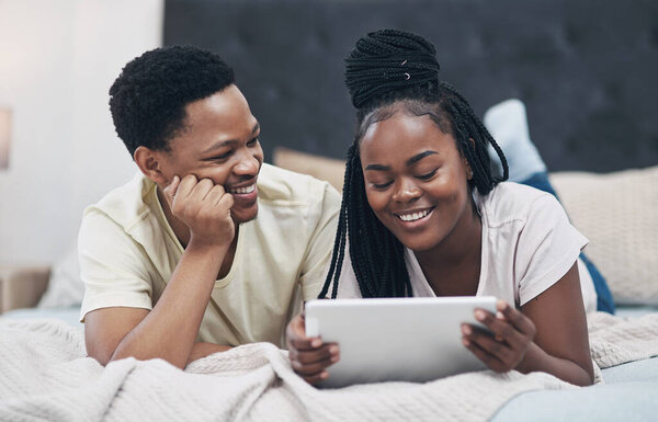 Блокировка - это весело, когда ты играешь с любимым человеком. молодая пара с помощью цифрового планшета во время отдыха на кровати дома