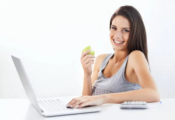 Portrait, laptop and woman nutritionist with apple in studio for wellness, diet or eating plan on white background. Weight loss, face and female health influencer with blog survey, help or menu guide.