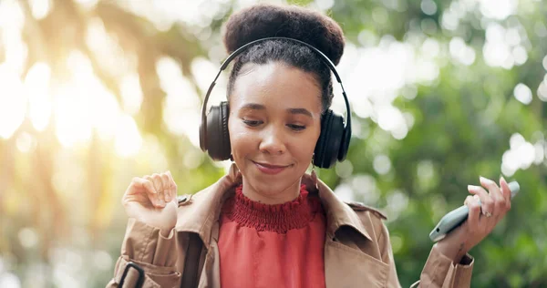Happy woman, phone and headphones in nature for music, audio streaming or outdoor sound track. Female person smile with technology on smartphone listening to podcast, playlist or songs at park.