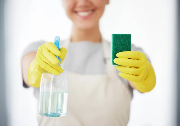 One unrecognizable woman holding a cleaning product and sponge while cleaning her apartment. An unknown domestic cleaner wearing latex cleaning gloves.
