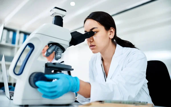 Clinical research and trials are fundamental tools of modern medicine. a young scientist using a microscope in a lab