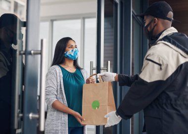 Yemek dağıtım işindeki en iyi ve en güvenli yer. Maskeli genç bir kadın eve paket servis alıyor.