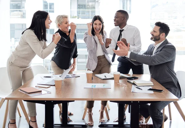 Every success is a team effort. a group of businesspeople cheering in a meeting at work