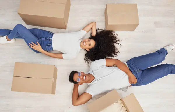 New beginnings loading. a young couple lying on the floor while unpacking boxes in their new house