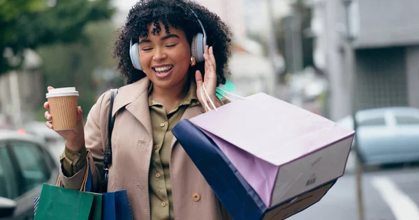 Headphones, shopping bag or happy woman in city for boutique retail sale, or clothes discount deal. Coffee, financial freedom or rich customer walking on street streaming radio music with fashion.