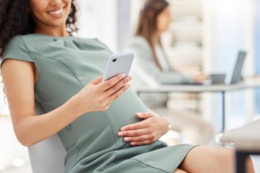 Bir sürü tebrik mesajı alıyorum. Ofiste cep telefonu kullanan hamile bir iş kadınının yakın plan fotoğrafı.