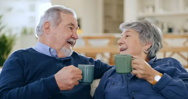Coffee, love and a senior couple in their home to relax together during retirement for happy bonding. Smile, romance or conversation with an elderly man and woman drinking tea in their living room.