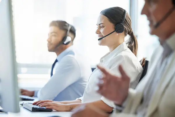 One of our friendly and experienced agents will be with you now. call center agents wearing headsets while sitting at their computers