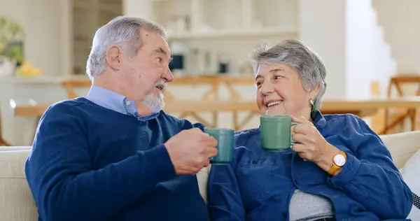 Tea, love and a senior couple in their home to relax together in retirement for happy bonding. Smile, romance or conversation with an elderly man and woman drinking coffee and toast in living room.