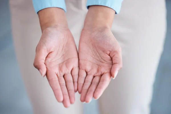 Above view and closeup of two hands extended with open palms in a giving and receiving gesture. Unknown mixed race businesswoman asking for help. Hispanic office professional offering support.