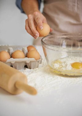 Kek yapmak için birkaç yumurta kırman gerekir. Mutfağındaki kaseye malzeme koyan bir kadının yakın plan fotoğrafı.