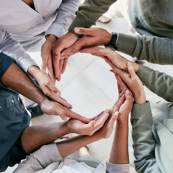 Success is the doing, not the getting. High angle shot of a group of unrecognizable businesspeople forming a circle with their hands at work
