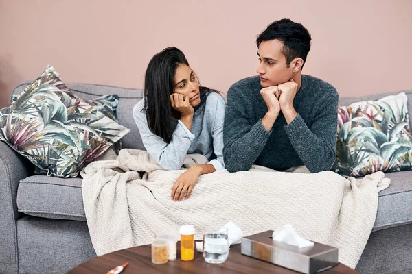 Self quarantine can lead to feelings of stagnation. a young couple sitting on the sofa while recovering from an illness at home