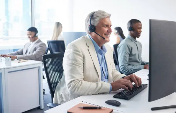 We have an amazing offer for you. a mature businessman using a headset and computer in a modern office