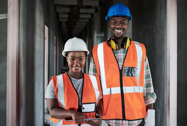 The harder we work the happier our clients are. a young man and woman using a digital tablet while working at a construction site