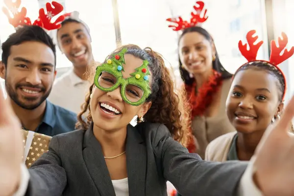 Its party time. a group of businesspeople taking a selfie during a Christmas party at work