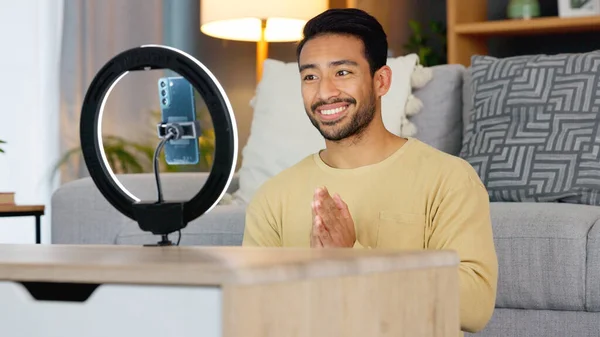 Influencer man, phone and ring light for talk, live stream or web chat in home living room. Content creator guy, video call or vlogger on cellphone, contact or recording in lounge, house or apartment.