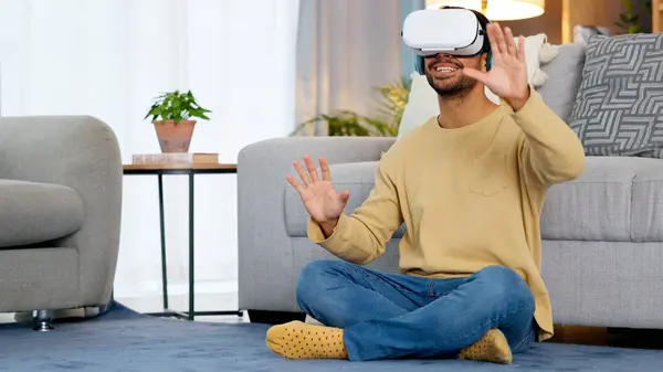 Home, virtual reality glasses and man on the floor, gaming and connection in a living room. Person, guy and player with esports, online gaming and VR eyewear with headphones, futuristic and relax.