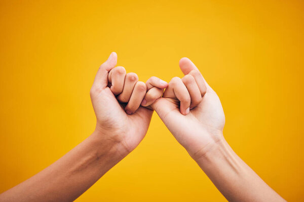 People, hands and pinky promise in studio with trust, help or hope for reconciliation on yellow background. Finger, emoji and deal by friends with secret, gesture and support expression or solidarity.
