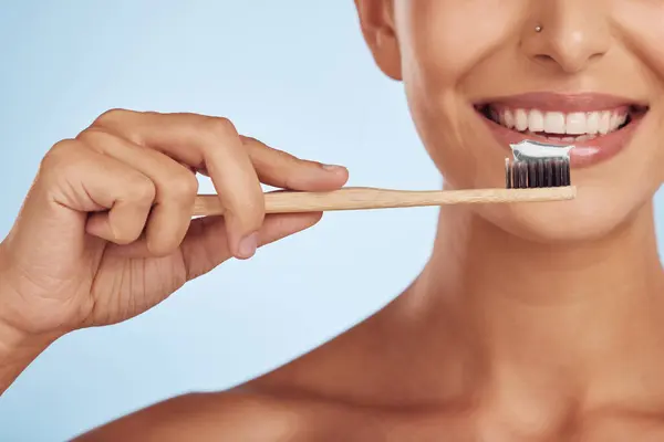 Happy woman, hands and toothbrush for dental care, health and wellness against a blue studio background. Closeup of person smile with brush for cleaning teeth, oral mouth and gum hygiene in self love.